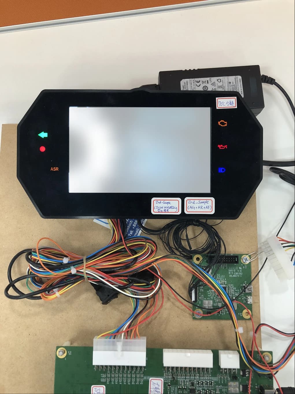 Dashboard HMI hardware sample on the bench, showing turn signal, engine, oil, and headlight icons